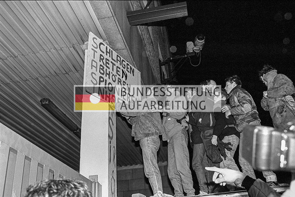 Einige Menschen stürmen die Stasi-Zentrale und hängen Protestplakate auf