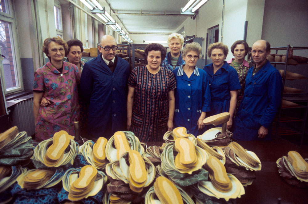 Eine Gruppe von Arbeiterinnen einer Schuherstellungsfabrik mit ihrem Vorgesetzten