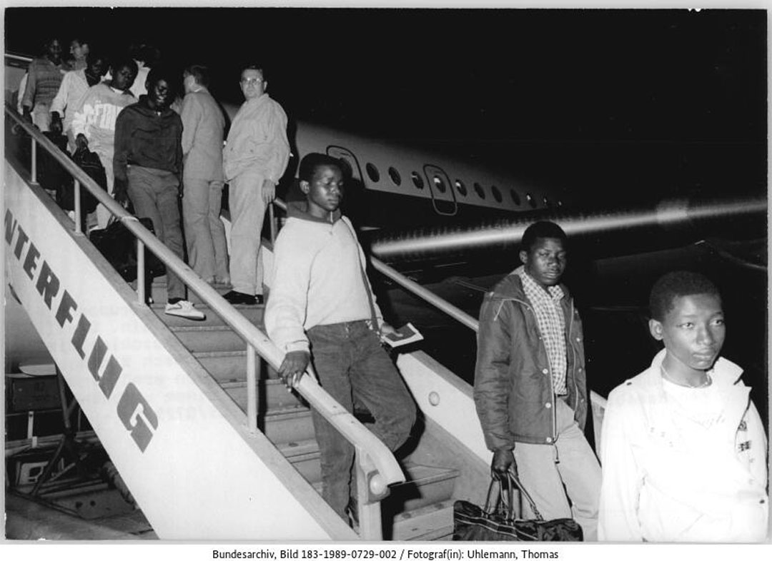 Mehrere junge Menschen aus Namibia gehen die Gangway eines Flugzeugs der DDR-Fluggesellschaft Interflug hinunter.