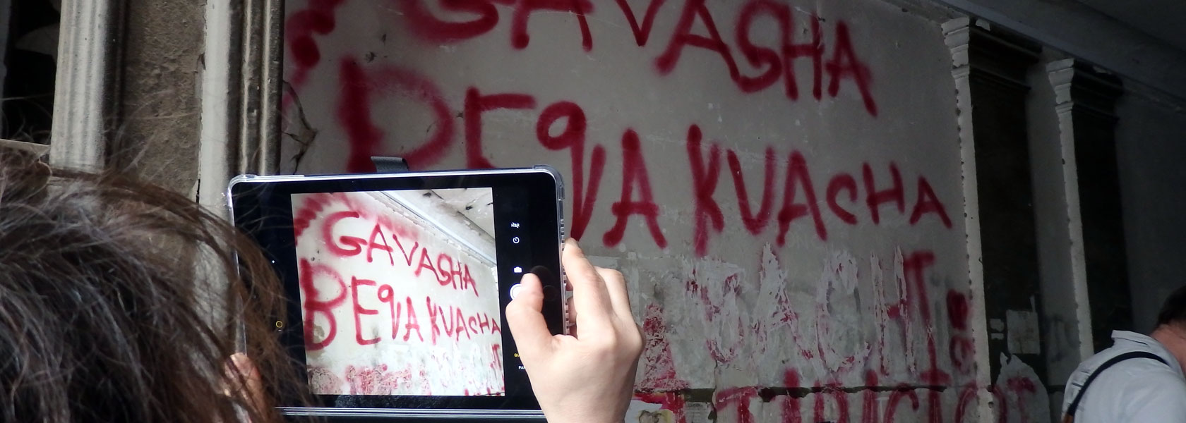 Ein Tablet, mit dem eine Frau einen Schriftzug an einer Wand fotografiert