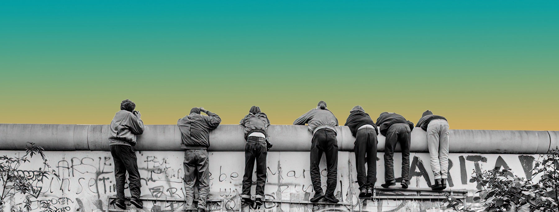 Jugendliche lehnen sich über die Berliner Mauer
