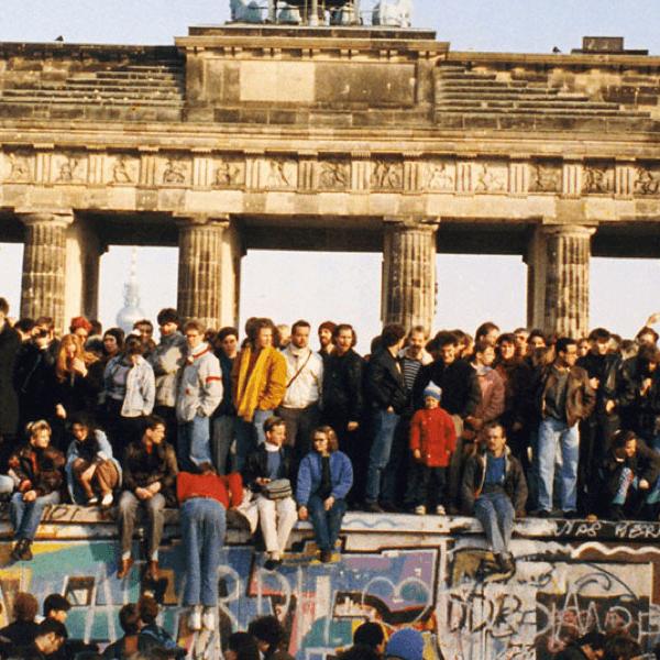 Menschen auf und vor der Berliner Mauer am Brandenburger Tor