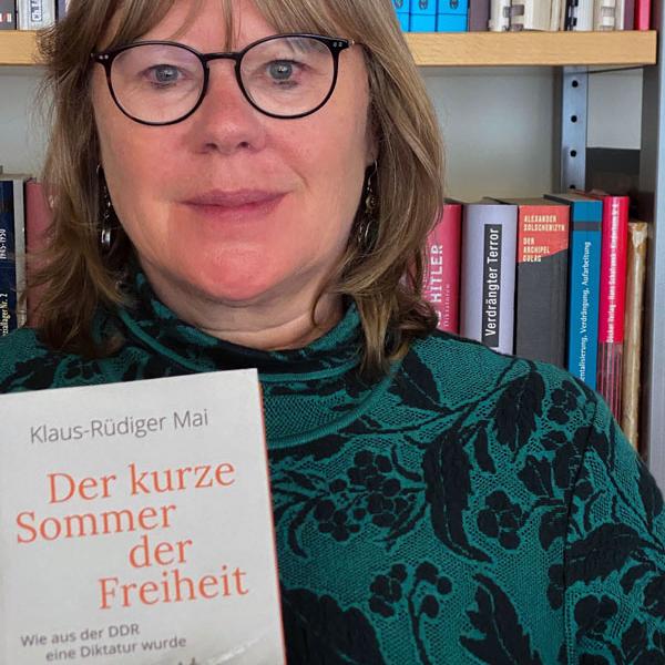 Dr. Anna Kaminsky hält das Buch "Der kurze Sommer der Freiheit" von Klaus-Rüdiger Mai in der Hand.