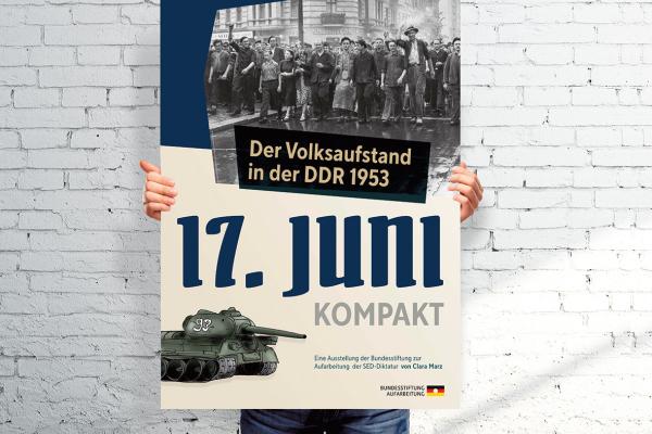 Person hält Plakat der Ausstellung: "17. Juni Kompakt. Der Volksaufstand in der DDR 1953." Eine Ausstellung der Bundesstiftung zur Aufarbeitung der SED-Diktatur von Clara Marz