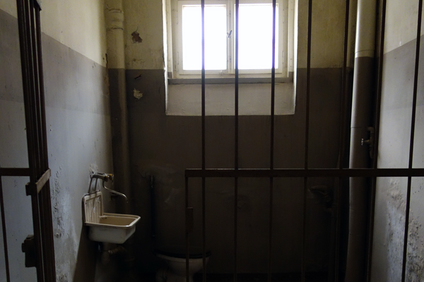 Gitterstäbe und ein kleiner Raum mit Waschbecken und Fenster