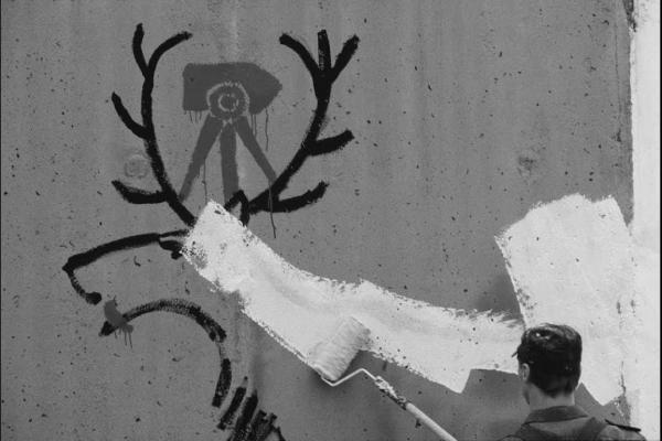 Ein auf einer Wand gezeichneter Hirsch, der mit weißer Farbe übermalt wird