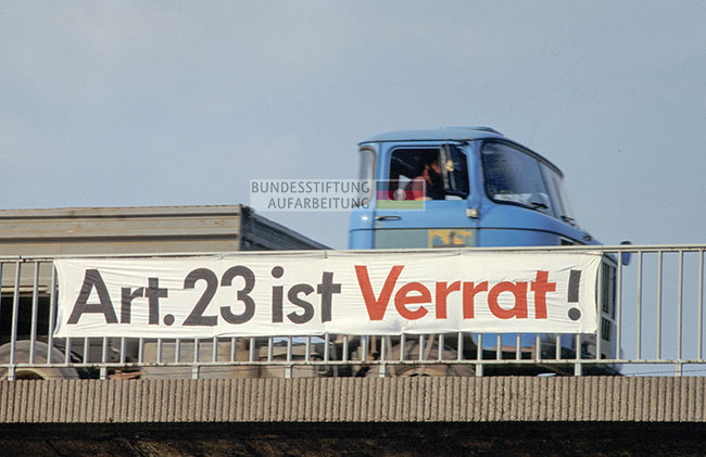 An einer Autobahnbrücke des Berliner Rings hängt 1990 ein Banner gegen die schnelle Wiedervereinigung mit dem Titel „Art. 23 ist Verrat!“.